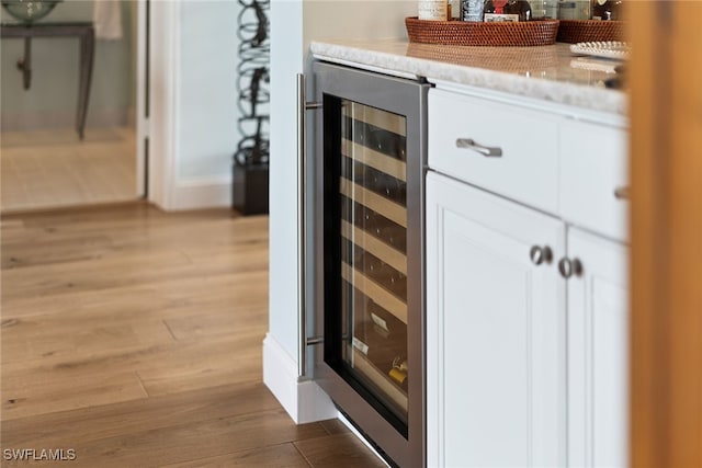 interior details featuring wine cooler, white cabinetry, and light wood-type flooring