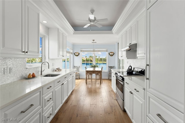 kitchen with wood-type flooring, sink, electric stove, hanging light fixtures, and white cabinetry