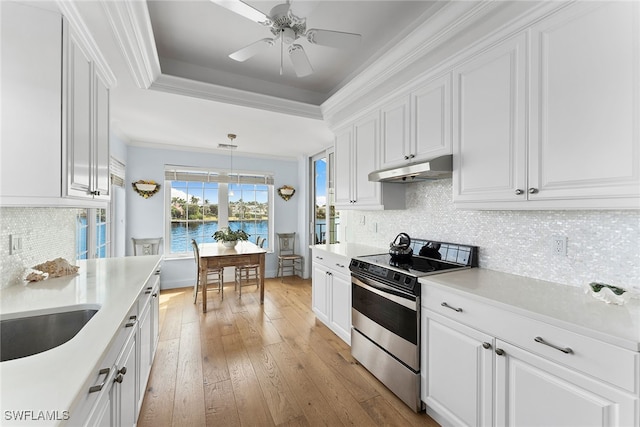 kitchen featuring white cabinets, light wood-type flooring, pendant lighting, stainless steel range, and a water view