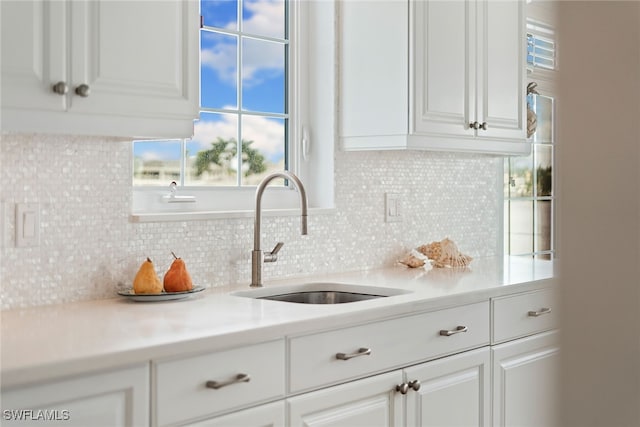 kitchen featuring white cabinetry, backsplash, and sink