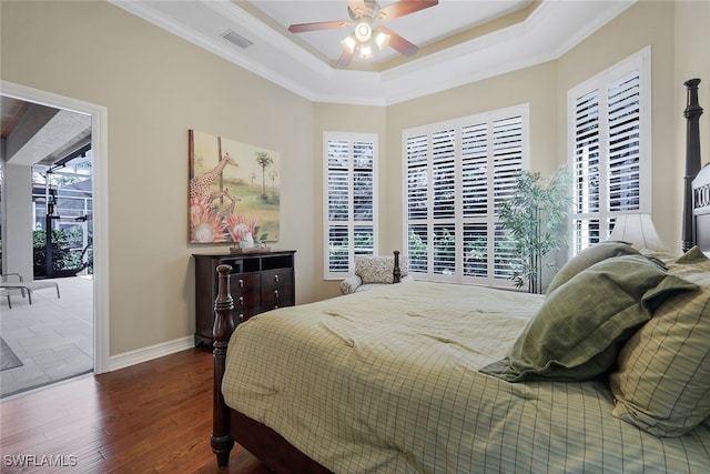 bedroom featuring dark wood-type flooring, a tray ceiling, crown molding, and ceiling fan