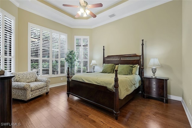 bedroom featuring ceiling fan, a tray ceiling, dark hardwood / wood-style floors, and crown molding