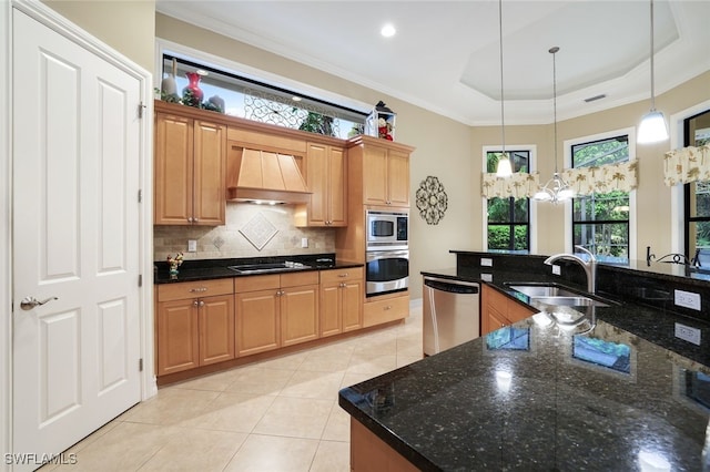 kitchen with custom range hood, plenty of natural light, dark stone countertops, and appliances with stainless steel finishes