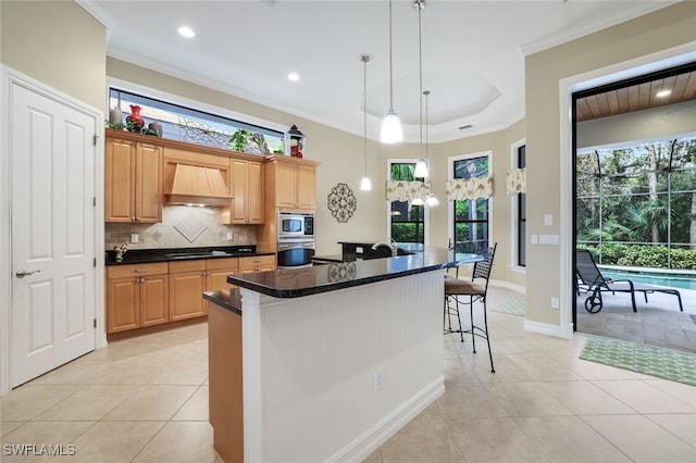 kitchen with an island with sink, custom exhaust hood, appliances with stainless steel finishes, and a healthy amount of sunlight