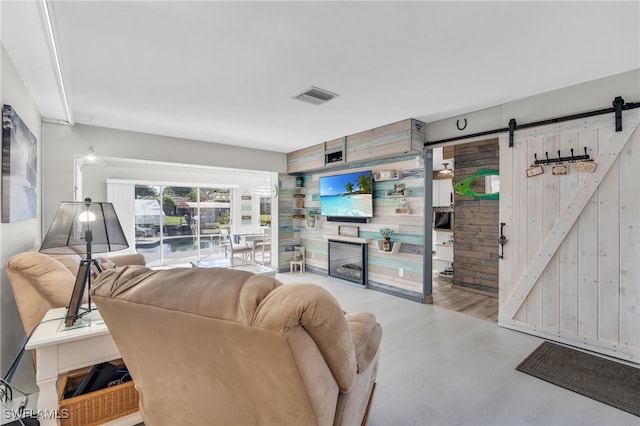 living room featuring wooden walls, a barn door, and wood-type flooring