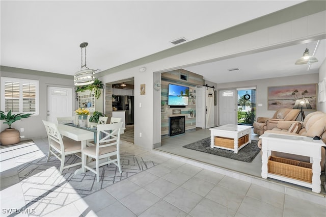 tiled dining area with a fireplace, plenty of natural light, and a barn door