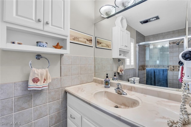 bathroom with vanity, tile walls, and a shower with shower door