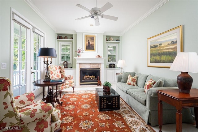 living area with a ceiling fan, crown molding, and a glass covered fireplace