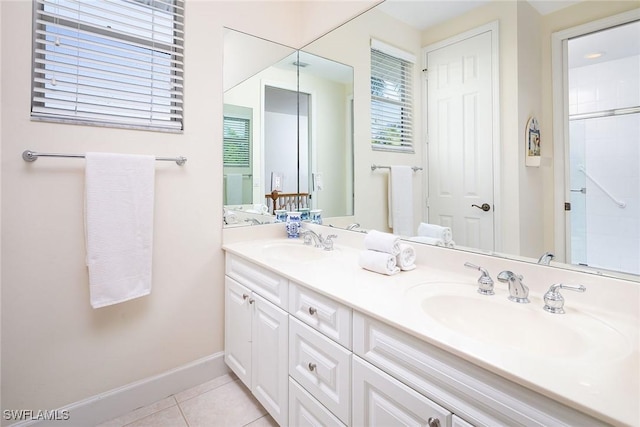 full bath with double vanity, a sink, baseboards, and tile patterned floors