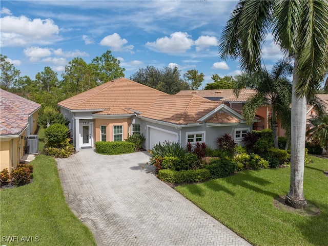 view of front of property featuring a front yard, cooling unit, and a garage