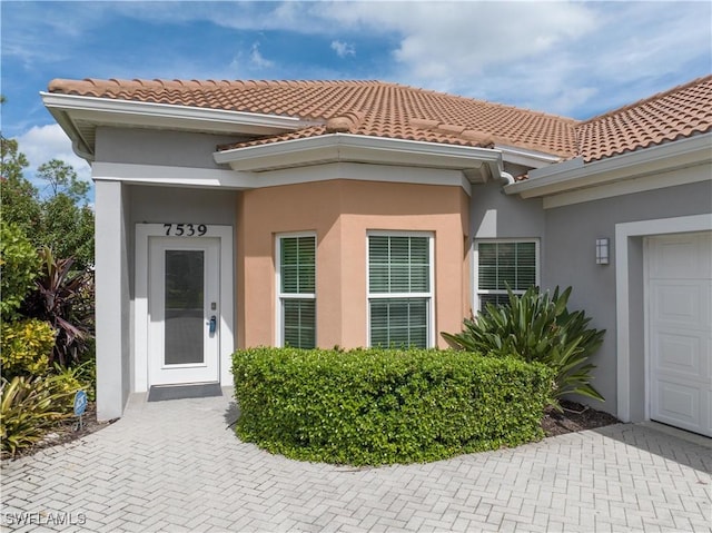 7539 Key Deer Ct, Fort Myers, FL 33966 - entrance to property featuring an attached garage, stucco siding, and a tile roof