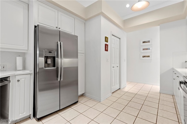 kitchen with appliances with stainless steel finishes, backsplash, light tile patterned flooring, and white cabinets