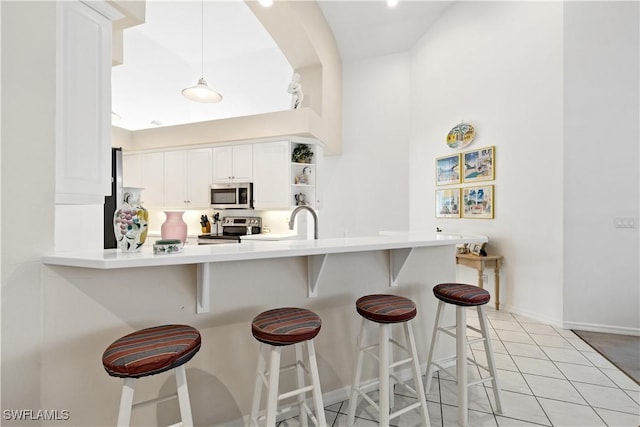7539 Key Deer Ct, Fort Myers, FL 33966 - kitchen with a peninsula, open shelves, white cabinets, a kitchen bar, and appliances with stainless steel finishes