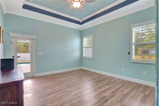 spare room with ceiling fan, light hardwood / wood-style floors, ornamental molding, and a tray ceiling