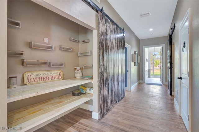 hallway with a barn door and light hardwood / wood-style flooring