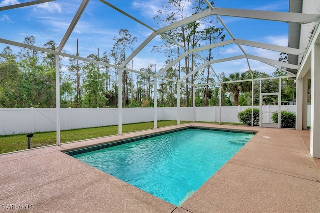 view of pool with a lawn, glass enclosure, and a patio area