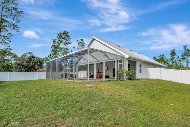 rear view of property featuring a lawn, glass enclosure, a patio area, and ceiling fan