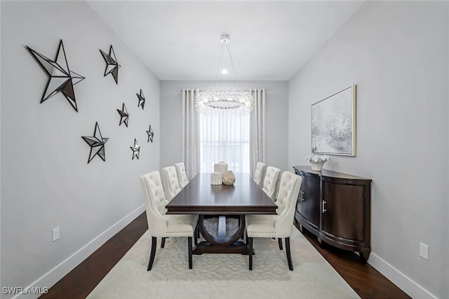 dining area with hardwood / wood-style flooring and an inviting chandelier