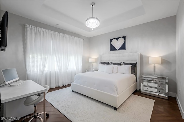 bedroom with a raised ceiling and dark parquet flooring