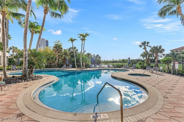 pool with a patio area, fence, and a hot tub