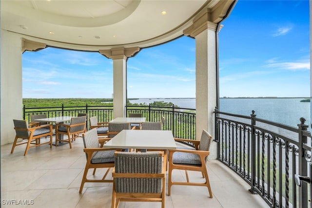 balcony with outdoor dining area and a water view