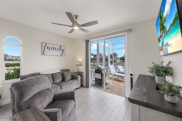 living room with ceiling fan, plenty of natural light, and light hardwood / wood-style flooring