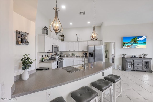 kitchen featuring pendant lighting, a kitchen breakfast bar, white cabinets, appliances with stainless steel finishes, and light tile patterned floors