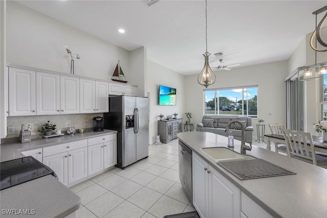 kitchen with hanging light fixtures, sink, stainless steel appliances, and white cabinets