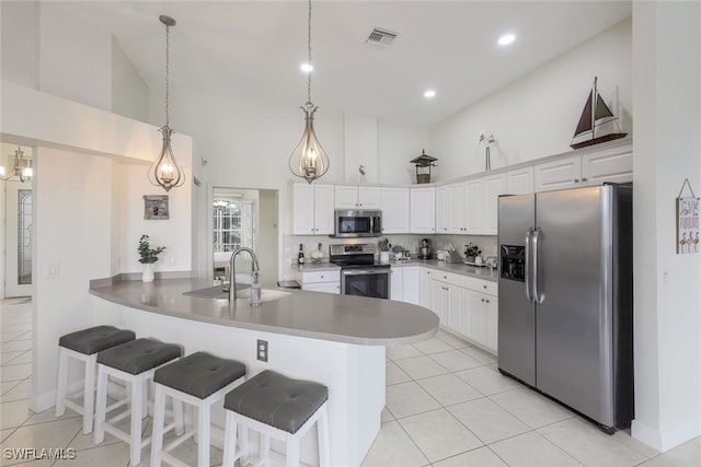 kitchen featuring appliances with stainless steel finishes, kitchen peninsula, hanging light fixtures, and white cabinets