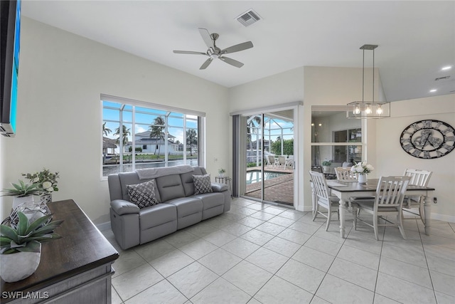 tiled living room featuring ceiling fan with notable chandelier and vaulted ceiling