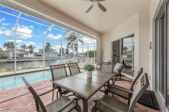 sunroom with ceiling fan, a swimming pool, and a water view