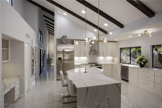 kitchen with appliances with stainless steel finishes, sink, light stone counters, a large island, and wall chimney range hood