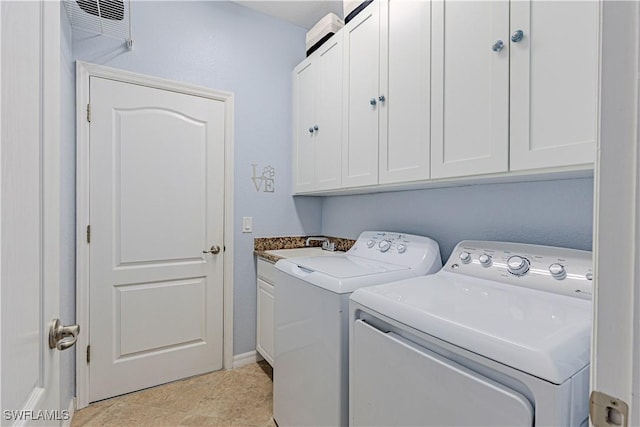 clothes washing area with separate washer and dryer and cabinets