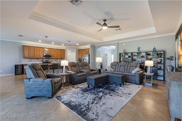 tiled living room with a raised ceiling, ceiling fan, and ornamental molding