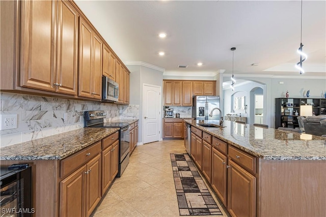 kitchen with a large island, appliances with stainless steel finishes, hanging light fixtures, stone counters, and sink