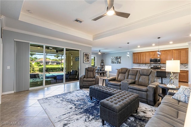 living room with crown molding, ceiling fan, a tray ceiling, and light tile patterned floors