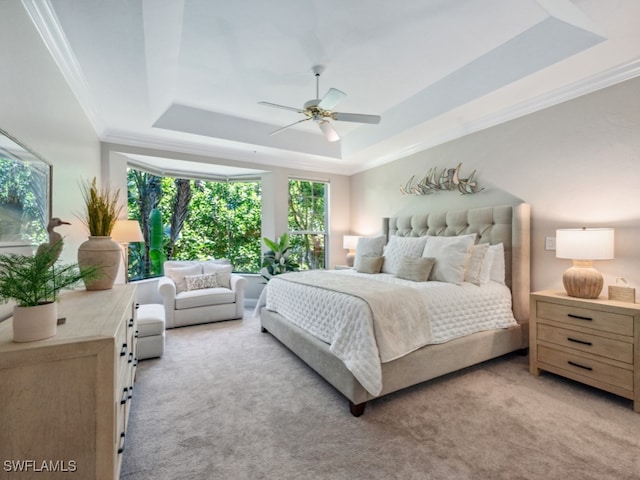 carpeted bedroom with a raised ceiling, ceiling fan, and crown molding