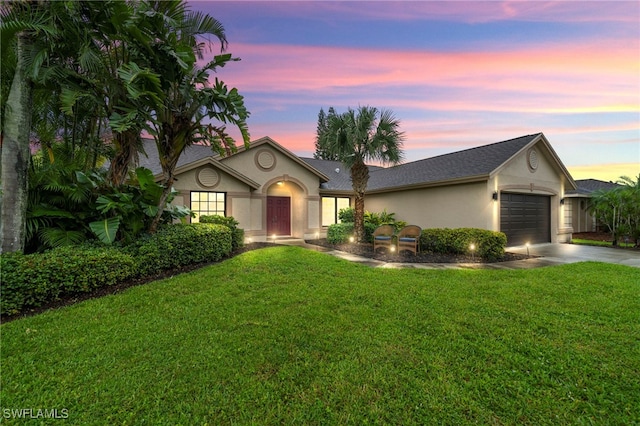 ranch-style house featuring a garage and a yard