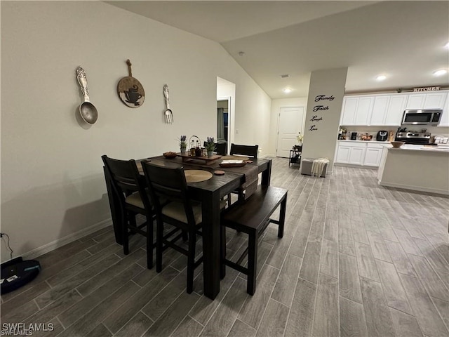 dining space with vaulted ceiling and hardwood / wood-style floors