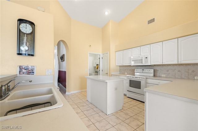 kitchen featuring sink, white cabinets, a kitchen island, high vaulted ceiling, and white appliances