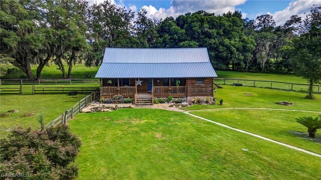 view of front of property with a rural view, a deck, and a front lawn