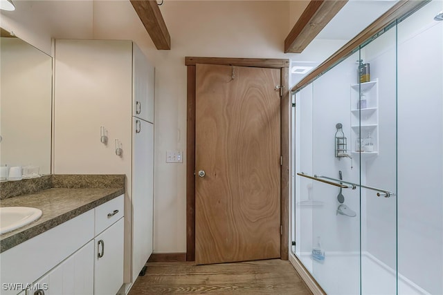 bathroom featuring vanity, beamed ceiling, hardwood / wood-style floors, and a shower with door