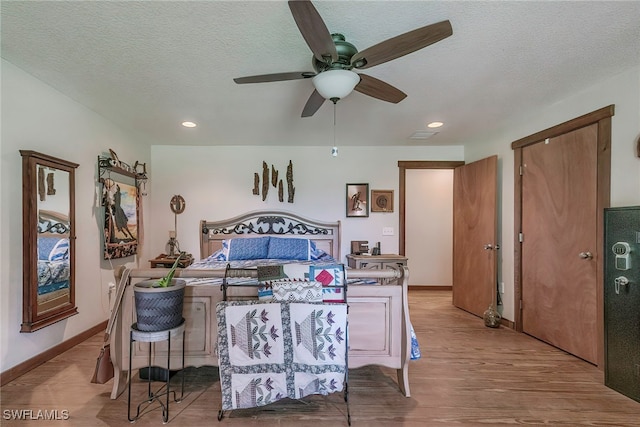 bedroom featuring light wood-type flooring, ceiling fan, and a textured ceiling