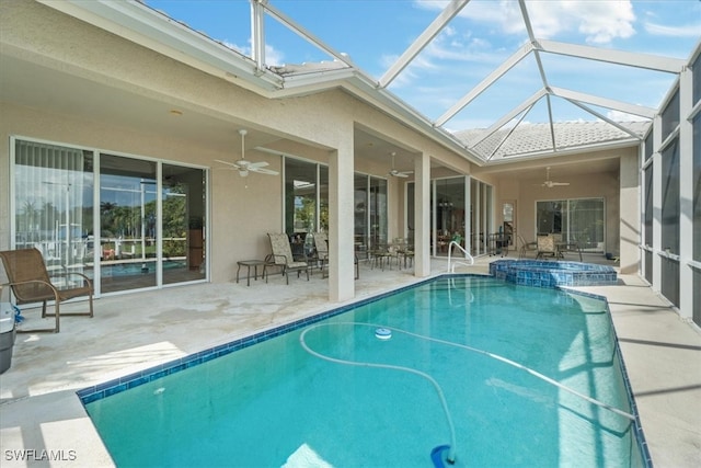 view of pool with an in ground hot tub, glass enclosure, ceiling fan, and a patio area