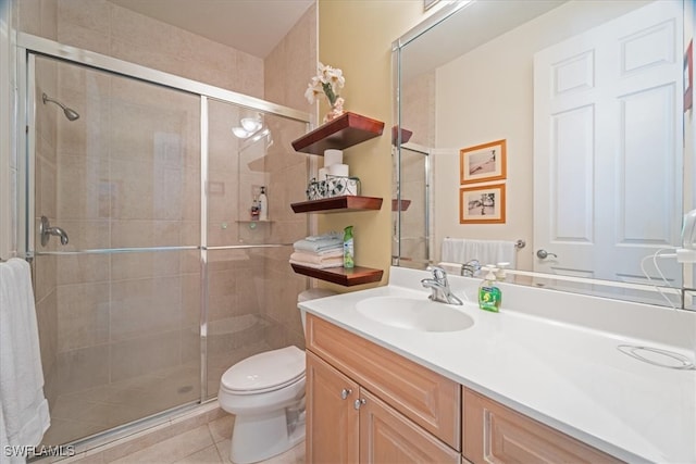 bathroom with tile patterned flooring, vanity, toilet, and a shower with door