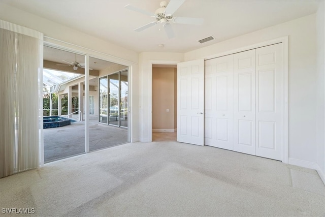 unfurnished bedroom with access to outside, a closet, light colored carpet, and ceiling fan