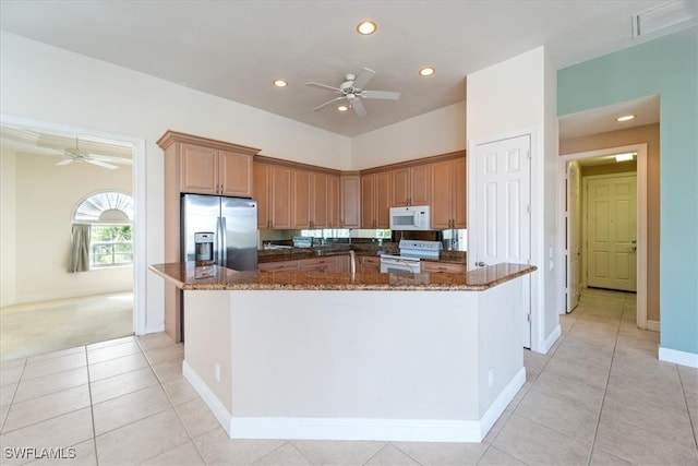 kitchen with a kitchen island, dark stone countertops, white appliances, and light tile patterned floors