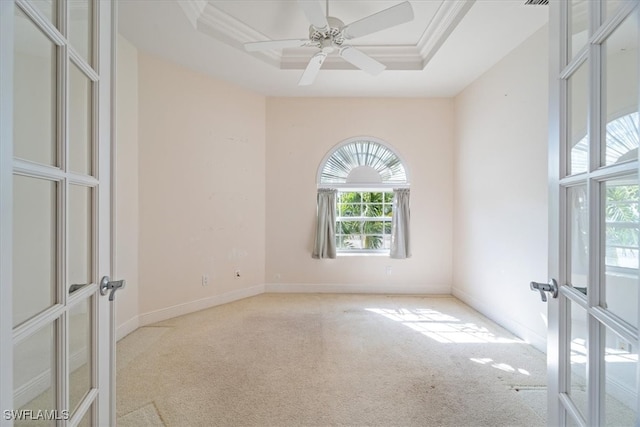 spare room with plenty of natural light, ornamental molding, a tray ceiling, and french doors