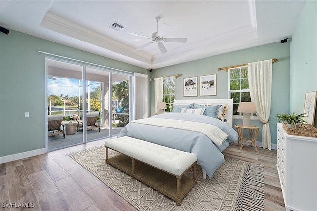 bedroom featuring a raised ceiling, access to exterior, ceiling fan, and light hardwood / wood-style flooring