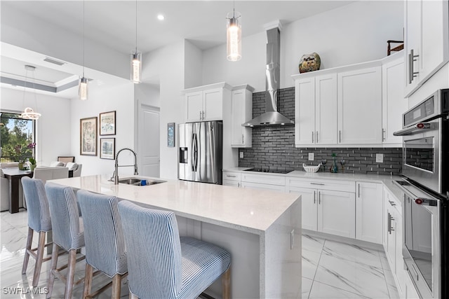 kitchen featuring pendant lighting, an island with sink, sink, white cabinetry, and appliances with stainless steel finishes